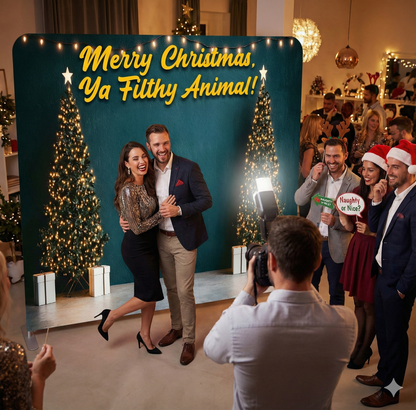 Group of people posing in front of a Christmas-themed backdrop with text and decorations.