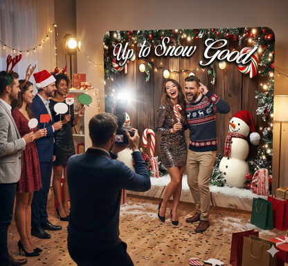 Group of people celebrating Christmas with a photo booth backdrop featuring festive decorations.