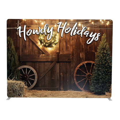 Decorative backdrop with 'Howdy Holidays' text, wooden wagon, Christmas tree, and lights.